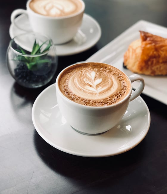 Cup of delicious coffee with froth on breakfast in cafeteria